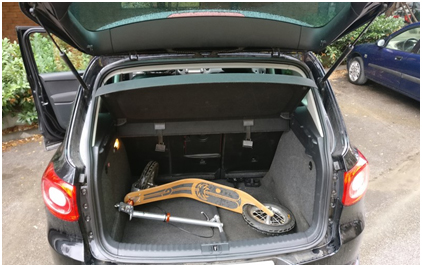 folded boardy scooter stored in a car trunk, showing how several scooters fit easily into an average-size car.