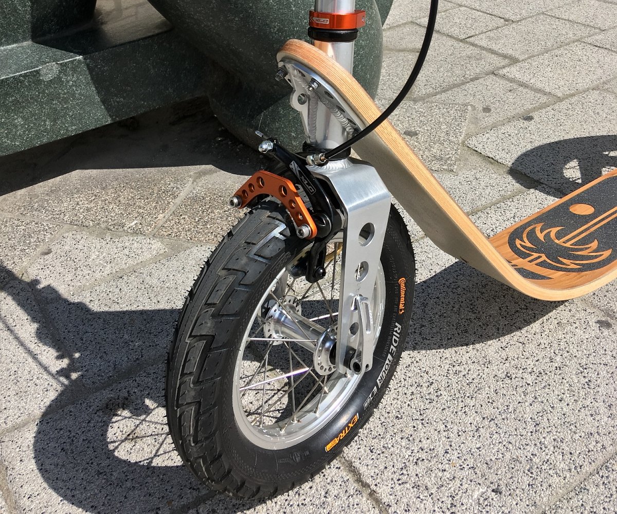 close-up of the boardy scooter’s flexible wooden frame and large pneumatic wheel showing its shock-absorbing design.