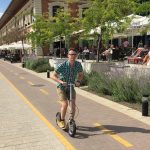 Man riding a Boardy scooter with a flexible wooden frame on a city bike path in Budapest.