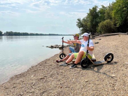 relaxing by the riverside with their boardy scooters beside them.
