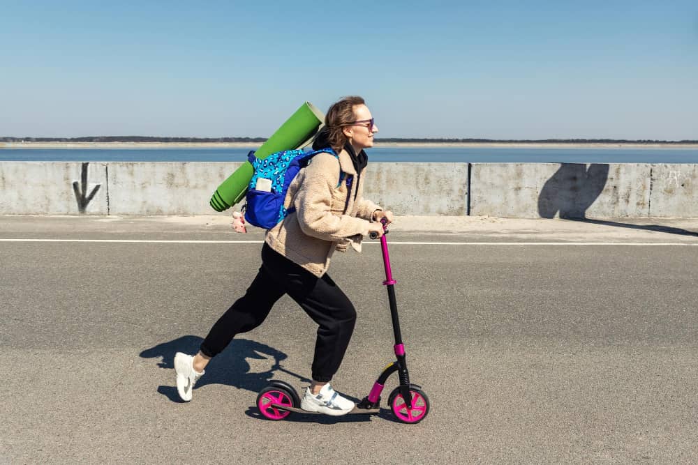 push scooters for adults - woman using kick scooter on road