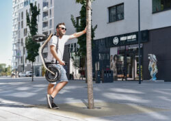 Take It With You a man holding a folded boardy and leaning against a tree