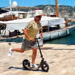 Smooth Moves At The Marina man pushing off on a boardy - the fastest kickscooter - in front of luxury yachts at a marina.