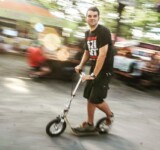 Rolling Through Rhythm man riding a boardy adult scooter at sziget festival, with motion blur in the background capturing the energy of the event.