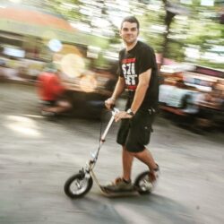 Rolling Through Rhythm man riding a boardy adult scooter at sziget festival, with motion blur in the background capturing the energy of the event.