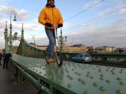 The Broader Meaning Of All-Terrain person riding a boardy all-terrain kick scooter in an urban setting.