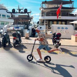 Dockside Ride rider near a jacht with a boardy scooter on a dock.