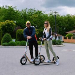 Park Pause two riders with boardy scooters chatting in a park.