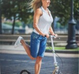 City Stroll alexandra beres riding a boardy scooter down a city street.